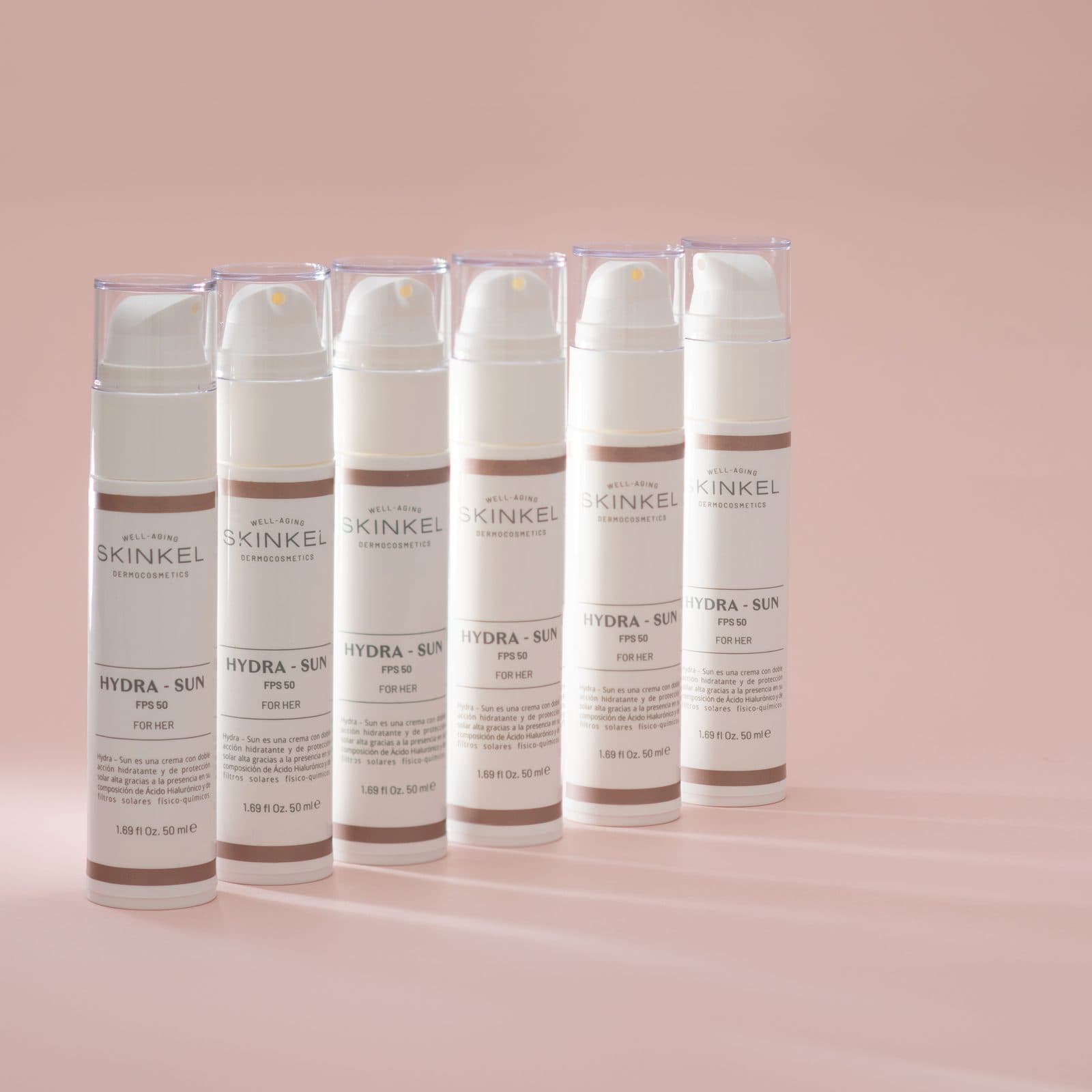 Envases de Hydra-Sun SPF 50 en fila sobre fondo rosa